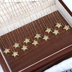 Star-shaped gold pendants with zircon initials on a wooden jewelry display case