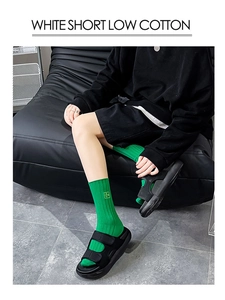 Gros plan de chaussettes en coton vert vif portées avec des sandales noires