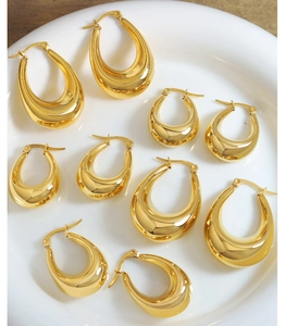 Detailed view of polished gold U-shape teardrop earrings on a white ceramic tray