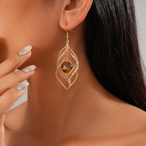 Close-up of a model wearing gold hollow rhombus earrings with brown tiger eye beads