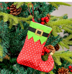 Détail d'une chaussette de Noël rouge à pois suspendue à un sapin décoré