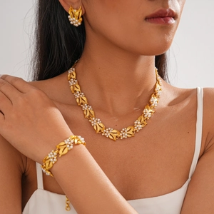 Close-up of golden leaf jewelry set with white pearls and sparkling zircons on model
