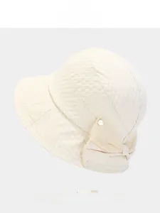 Detail of cream bow bucket hat with unique honeycomb texture and small metal charm