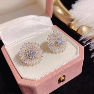Sparkling zircon sunflower stud earrings in gold finish displayed on pink velvet