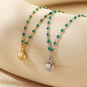 Macro view of gold and silver shell pendants with white pearls and green beads