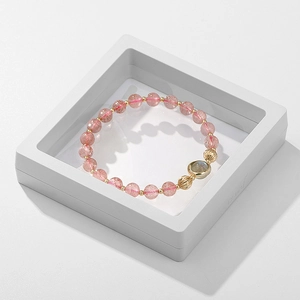 Pink beaded bracelet with gold accents displayed in a white floating jewelry box