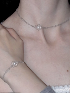 Nahaufnahme der minimalistischen silbernen Blumenhalskette und des Armbandes mit Perlen