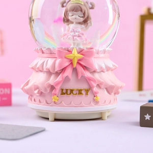 Detailed view of pink music box snow globe featuring a lucky bow and girl figurine