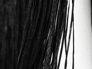 Nahaufnahme eines schwarzen Samt-Neckholder-Tops mit Netzgewebe und Fransen-Details