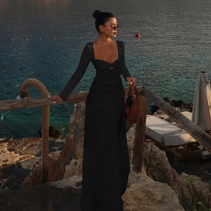 Detail of black hollow-out long sleeve dress against a sunset beach landscape