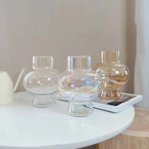 Three spherical glass vases in clear, iridescent, and amber finishes on a white table