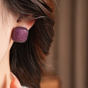 Détail d'une boucle d'oreille vintage carrée avec zircons violets sur métal sombre