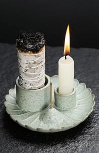 Macro detail of a celadon ceramic Palo Santo holder with sage bundle and candle on stone