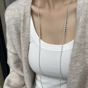 Detailed view of layered pearl sweater necklace worn over elegant knitwear for women