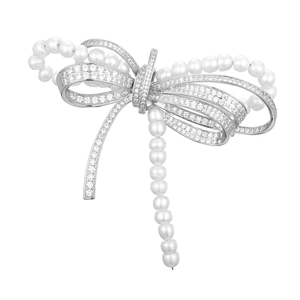 Macro shot of silver bow brooch with pavé cubic zirconia and white pearls detail