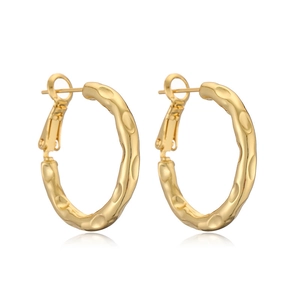 Close-up of gold C-shaped hoop earrings featuring a unique hammered metal texture finish