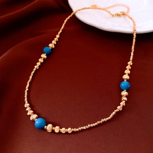 Détail d'un collier plaqué or 18 carats avec perles bleues sur tissu brun rouge