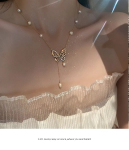 Detail view of a gold-plated butterfly necklace with white pearls and sparkling zircons