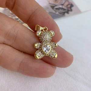 Close-up of golden bear pendant with heart-shaped gemstone and cubic zirconia pavé