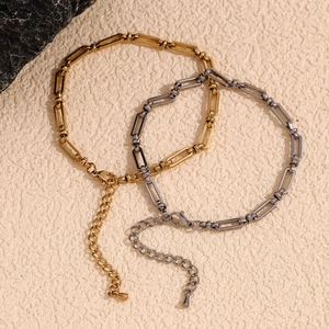 14K gold and silver stainless steel paperclip chain anklets on a beige textured background