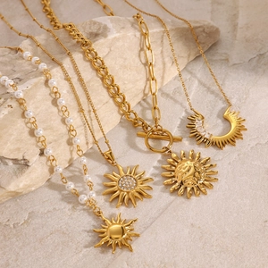 Elegant gold stainless steel necklaces with sun pendants and pearls on stone background