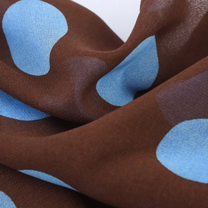 Detailed close-up of coffee brown chiffon fabric featuring light blue polka dot pattern