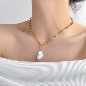 Detailed close-up of a white Baroque pearl pendant on a gold paperclip chain necklace