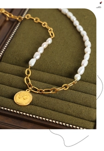 Macro detail of French vintage gold coin pendant and baroque pearl toggle necklace