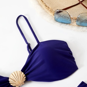 Detail of dark blue bikini top featuring a gold shell buckle and ruched fabric design