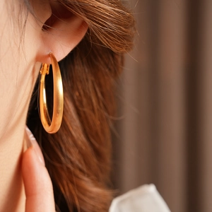 Close-up of a model wearing matte gold geometric round hoop earrings for women