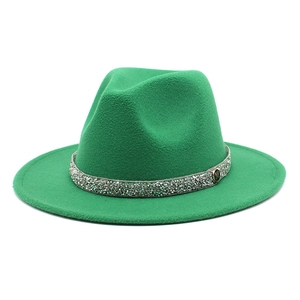 Detail of green wool fedora hat featuring a diamond-encrusted band and a metal M logo
