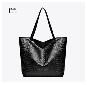 Detail of black tote bag featuring luxury crocodile pattern and polished PU leather texture