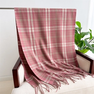 Detail shot of soft knit pink and beige plaid scarf featuring elegant tassel fringe trim