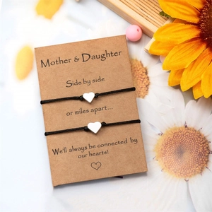 Bracelets mère et fille avec breloques cœur sur carte kraft avec détail tournesol