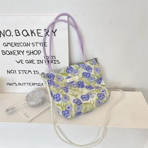 Dettaglio della borsa floreale con manici viola e tracolla di perle staccabile
