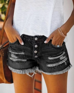 Dettaglio degli shorts in denim nero con strappi e chiusura a patta con bottoni multipli