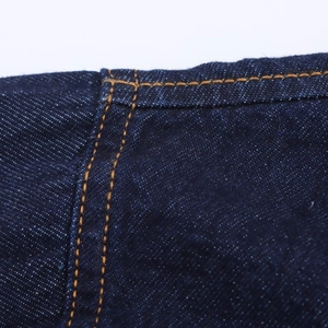 Détail du denim bleu foncé montrant le tissage haute densité et les doubles coutures