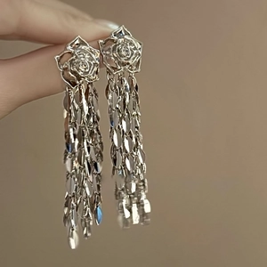 Gros plan sur des boucles d'oreilles rose argentée avec longs pompons feuilles