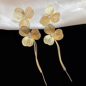 Detail of golden flower tassel earrings with zircons and long metallic fringe chains