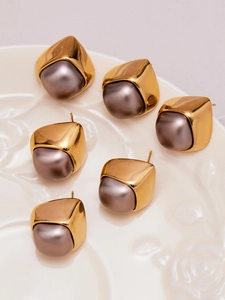 Detail view of 3 pairs of geometric gold earrings with matte grey pearls in a ceramic tray
