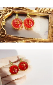 Macro detail of vintage red round stud earring with gold leaf inlay and green gem