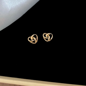 Detail of gold twisted heart earrings featuring intricate interwoven hollow design