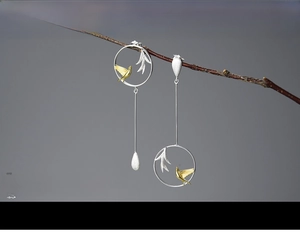 Detail of S925 silver asymmetrical dangle earrings with golden swallow and willow motifs