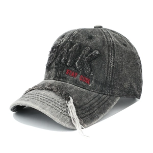 Détail d'une casquette en denim vieilli avec broderie 3D et bords effilochés usés