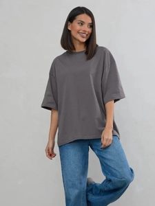 T-shirt oversize da donna in cotone grigio abbinata a jeans blu dritti in studio
