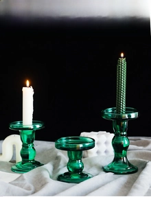 Close-up of three vintage green glass candle holders with elegant ribbed textures