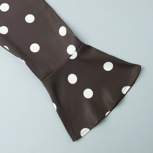 Détail du poignet à manches cloche avec imprimé à pois blancs classiques sur tissu noir