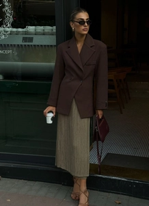 Dettaglio di un blazer marrone sagomato abbinato a una gonna a pieghe in stile urban chic