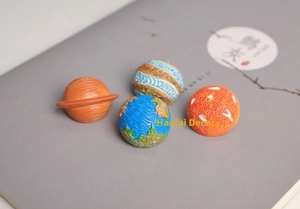 Macro shot of solar system planet badges on a book cover showing detailed Saturn and Earth