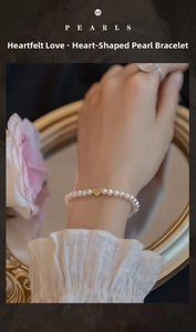 Close-up of elegant freshwater pearl bracelet with a gold heart pendant on model wrist